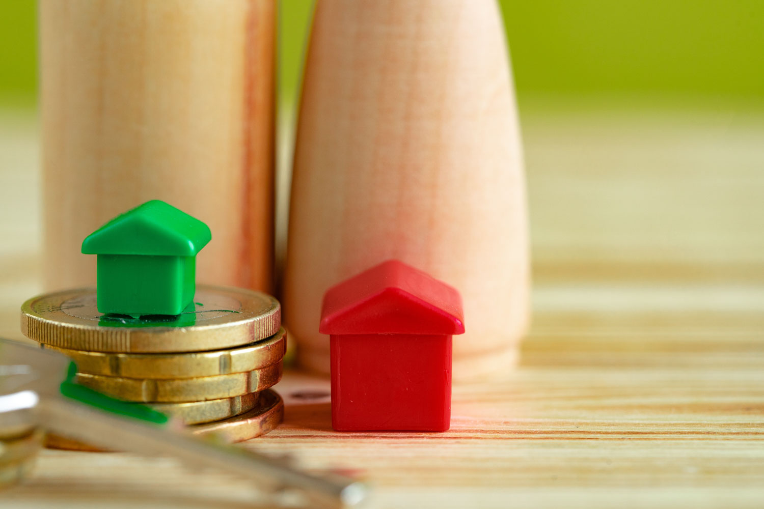 Wooden family with toy house and stack of coins close up. Savings for house purchase concept